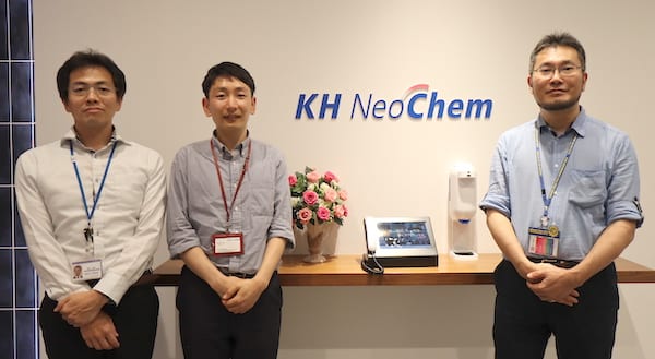 KH Neochem のロゴの前に立つ、ＫＨネオケム株式会社のご担当者 3 名の写真