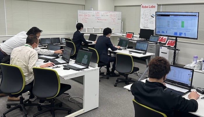 株式会社りそな銀行の「Robo Labo」の部屋。パソコンが並ぶ机で行員が作業している